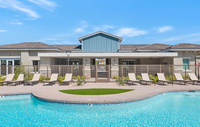 A swimming pool in front of a building with a blue sky in the background.