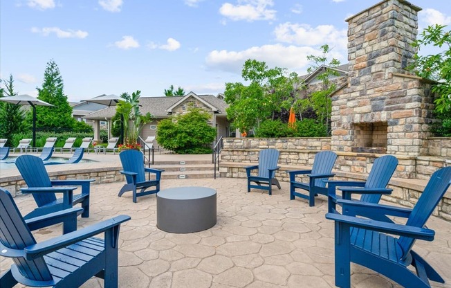 A patio with blue chairs and a fireplace.