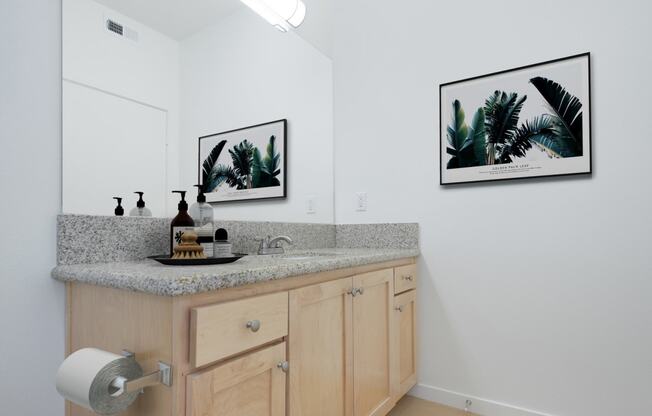 a bathroom with a granite counter top and two pictures on the wall