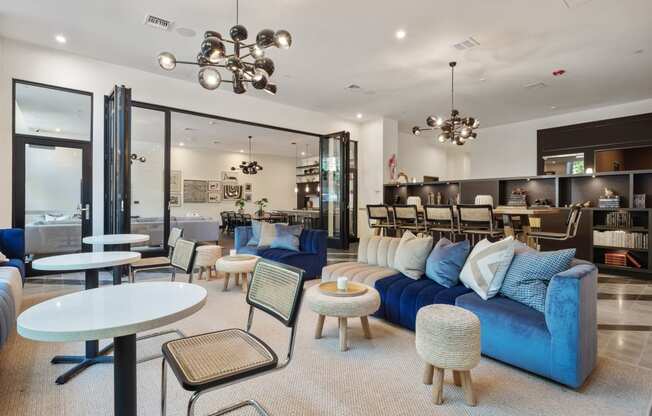 a living room with blue couches and tables and a dining room