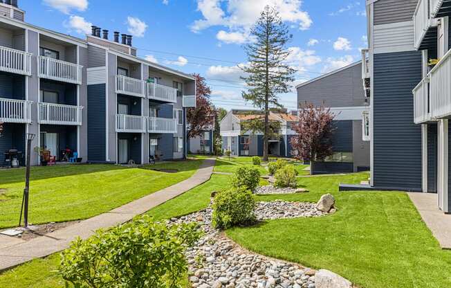 Apartment complex with a grassy area and a stone path.