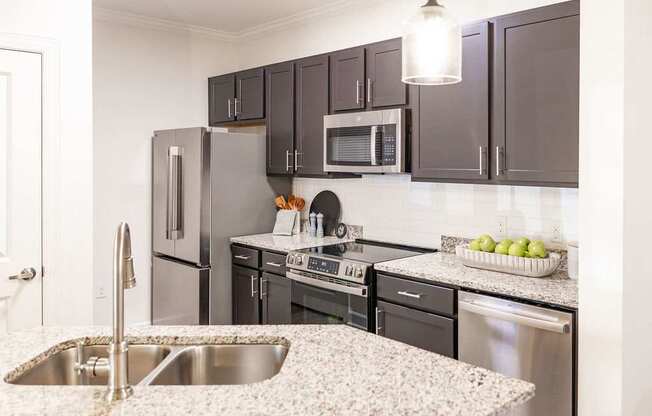 A kitchen with a sink, refrigerator, oven, and microwave.