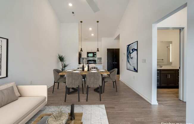 a dining area with a table and chairs and a kitchen in the background