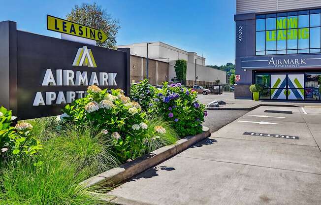 A sign for Airmark Apartments is displayed in front of a building with a leasing sign above it.