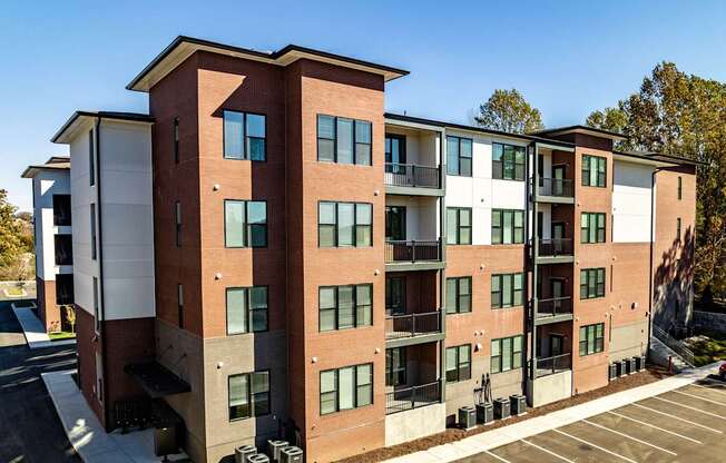 A large apartment building with a parking lot in front.