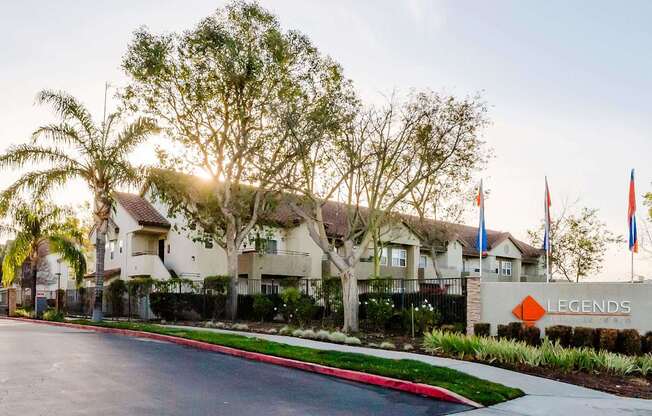 A sunny day at the Legends housing complex with palm trees and flags.