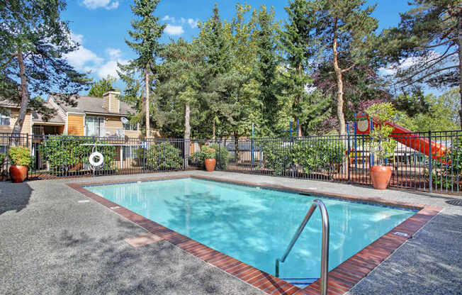 A small pool surrounded by a fence and trees.