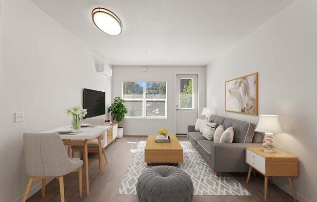 A living room with a grey couch, a wooden coffee table, a grey ottoman, a grey chair, a wooden dining table, a TV, a plant, a window, a painting, and a lamp.