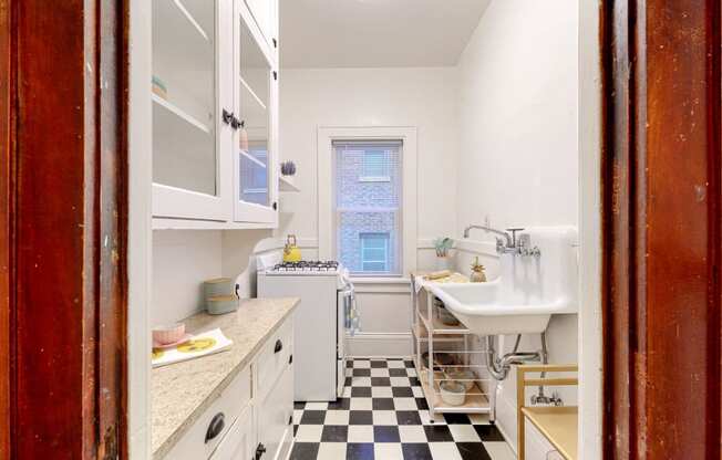 a small kitchen with white cabinets and a black and white checkered floor