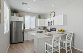 a kitchen with white cabinets and a white island with two stools