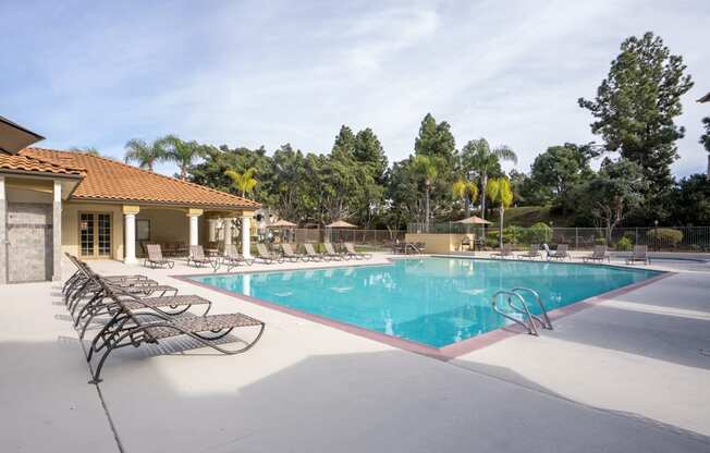 A large swimming pool with lounge chairs and a building in the background.