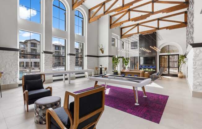 a living room with a pool table and large windows