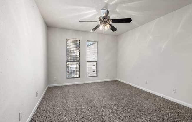 an empty living room with a ceiling fan and a window