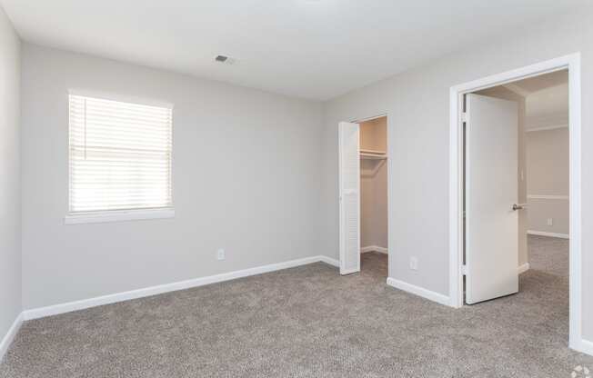 an empty bedroom with a closet and an open door