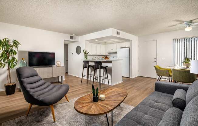 A living room with a grey sofa, a black chair, and a wooden coffee table.