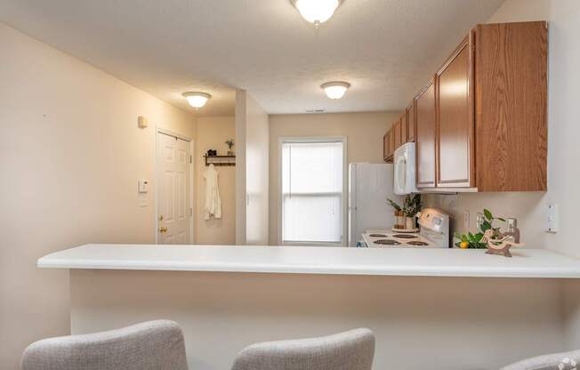 A kitchen with a white countertop and two grey chairs.