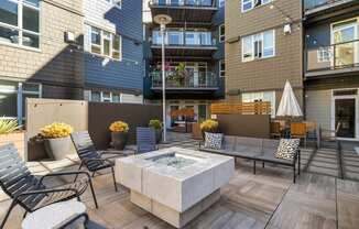A patio with a hot tub surrounded by chairs and potted plants.