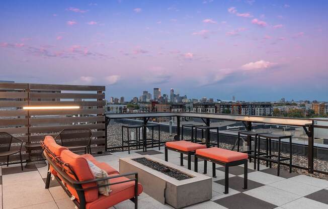 A rooftop patio with a bench, chairs, and a table.
