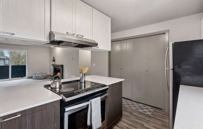 A modern kitchen with a black fridge and a stove with a pot on it.