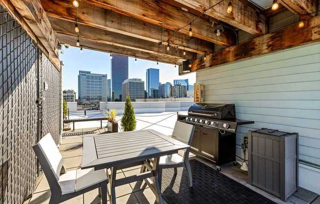 A patio with a table, chairs and a grill.