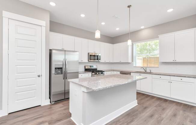 a kitchen with white cabinets and a large island with granite countertops