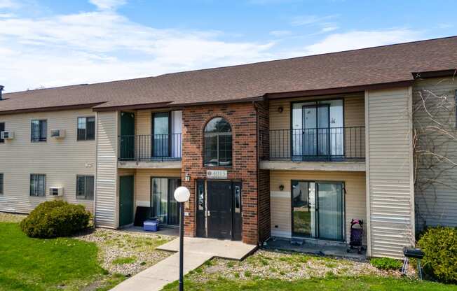 the front of a apartment building with a sidewalk and grass