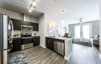 Kitchen overlooking living room with track ceiling lighting and modern light fixtures over kitchen island