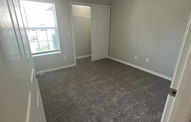 a bedroom with gray carpet and a window