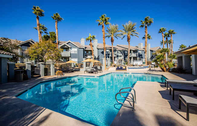 A swimming pool surrounded by palm trees and lounge chairs.