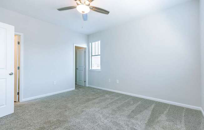 A room with a ceiling fan and carpeted floor.
