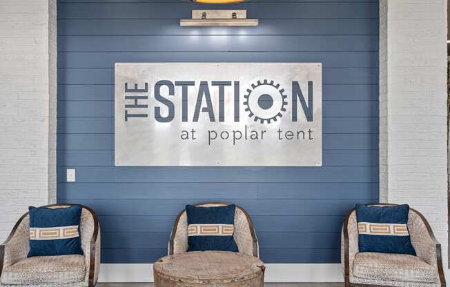 two chairs in front of a blue wall with the station at poplar tent logo