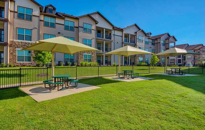 Park with tables and umbrellas and grass and building in back