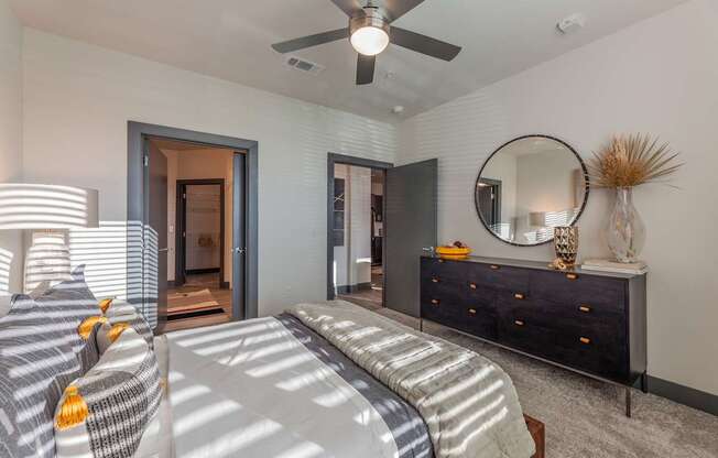 A bedroom with a bed, dresser, mirror, and a ceiling fan.