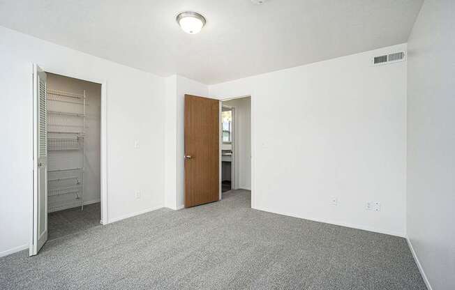 A bedroom with a carpeted floor and a walk-in closet with wardrobe organizers at Foxwood and The Hermitage in Portage, MI