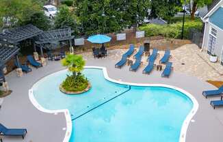 an aerial view of a resort style pool with lounge chairs and umbrellas