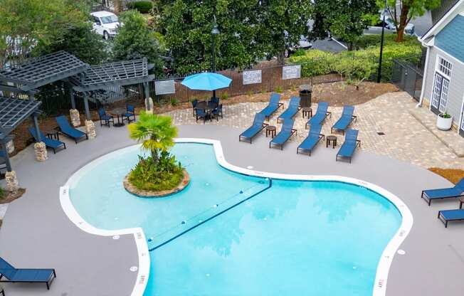 an aerial view of a resort style pool with lounge chairs and umbrellas