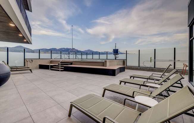 A rooftop patio with sun loungers and a view of the mountains.
