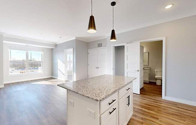 A kitchen with a granite countertop and wooden floors.