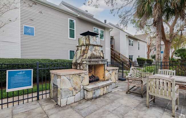 A stone fireplace is in the middle of a patio.