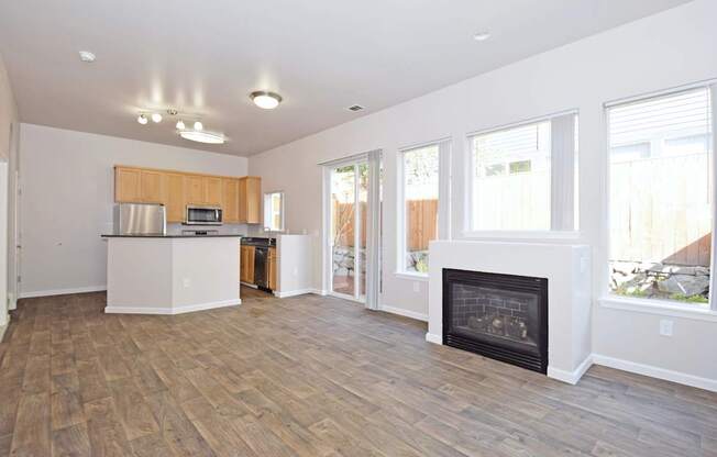 A living room with a fireplace and a kitchen area in the background.