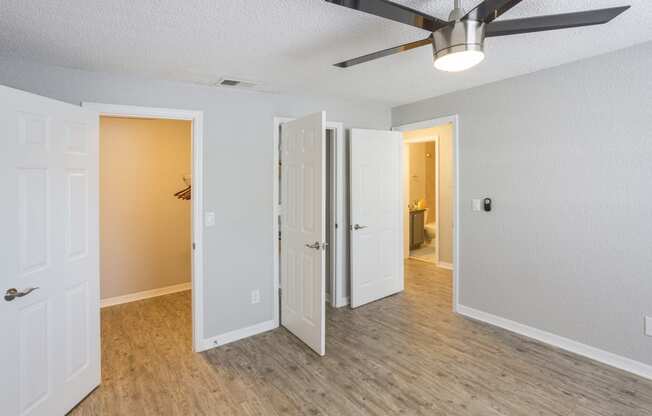 an empty bedroom with a ceiling fan and a door to a closet