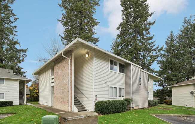 A house with a green trash bin in front of it.
