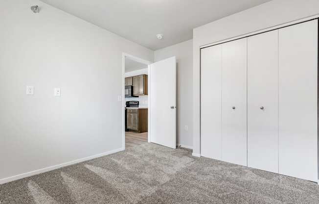 A room with white walls and a carpeted floor with a white door on the right.