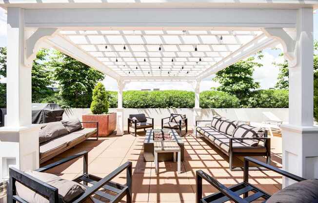 A white pergola with a patio furniture set underneath.