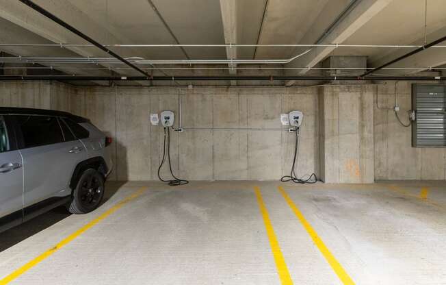 a car parked in a parking garage with two electric chargers plugged into the wall