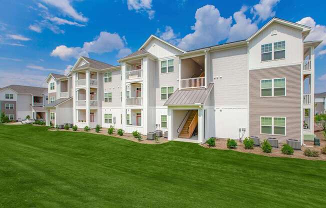 A large, modern apartment building with a green lawn in front.
