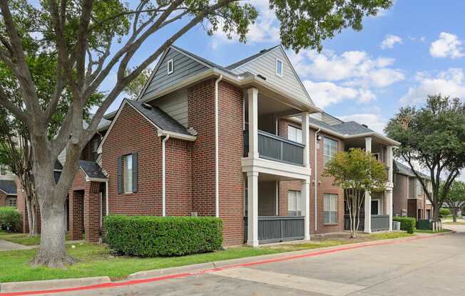A red brick apartment building with a tree in front.