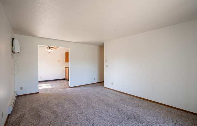 an empty living room with carpet and white walls. Fargo, ND Southview Village Apartments