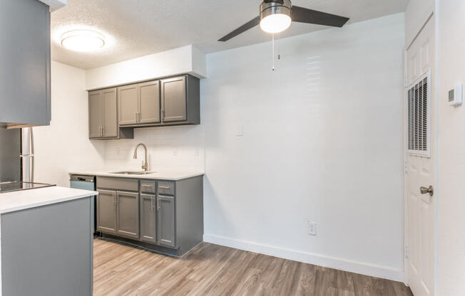 a kitchen and living room in an apartment with a ceiling fan