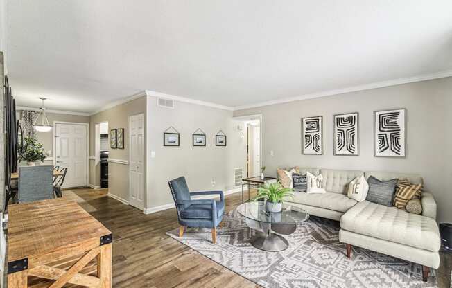 A living room with a couch, chairs, and pictures on the wall.